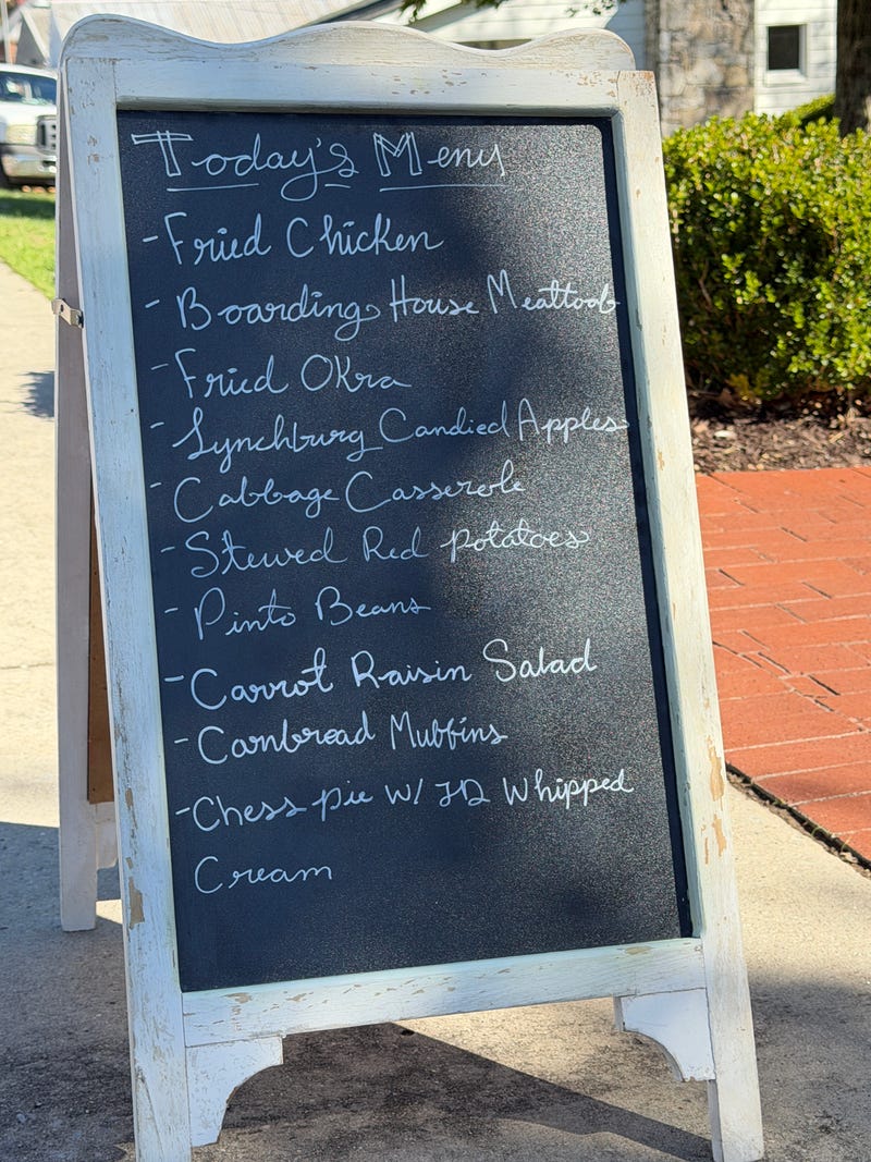 A rustic chalkboard menu on a sidewalk lists Southern dishes like fried chicken and chess pie. The setting feels cozy and inviting.