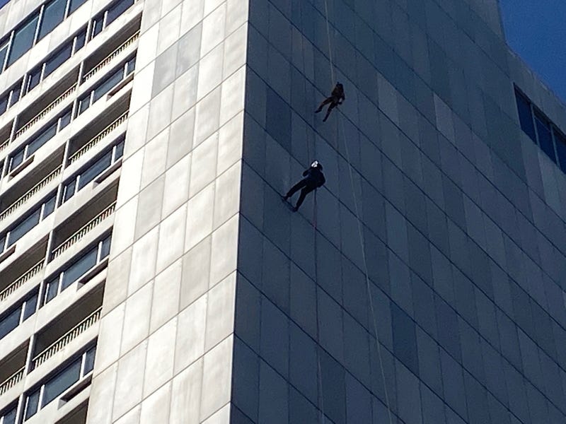 Two volunteers scale the side of the Hilton in San Francisco's Union Square.