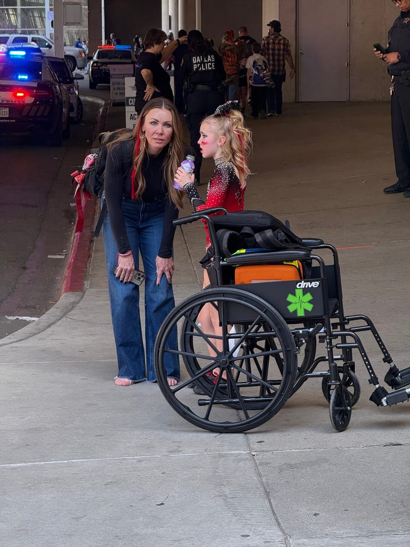 A cheerleader and her mom wait outside the Kay Bailey Hutchison Convention Center in Downtown Dallas