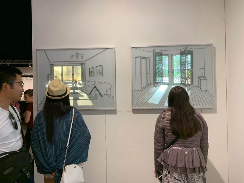 People looking very closely at paintings on a wall