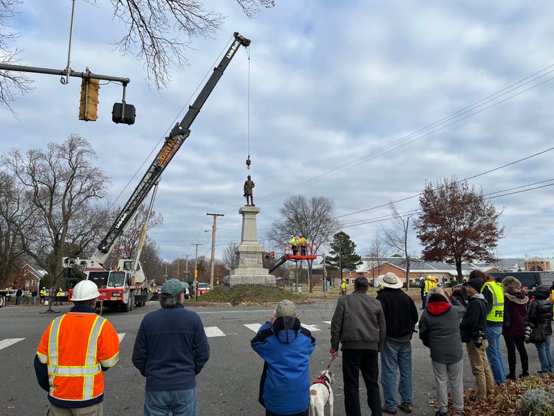 A crowd of reporters, city officials, and locals watch as the monument's removal commences