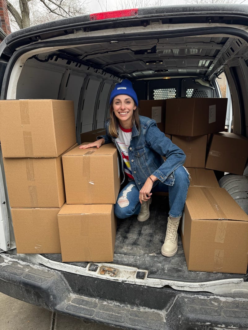 Laura Gardner poses with boxes of Local Style Potato Chips. The chips launched on April 3, 2025.
