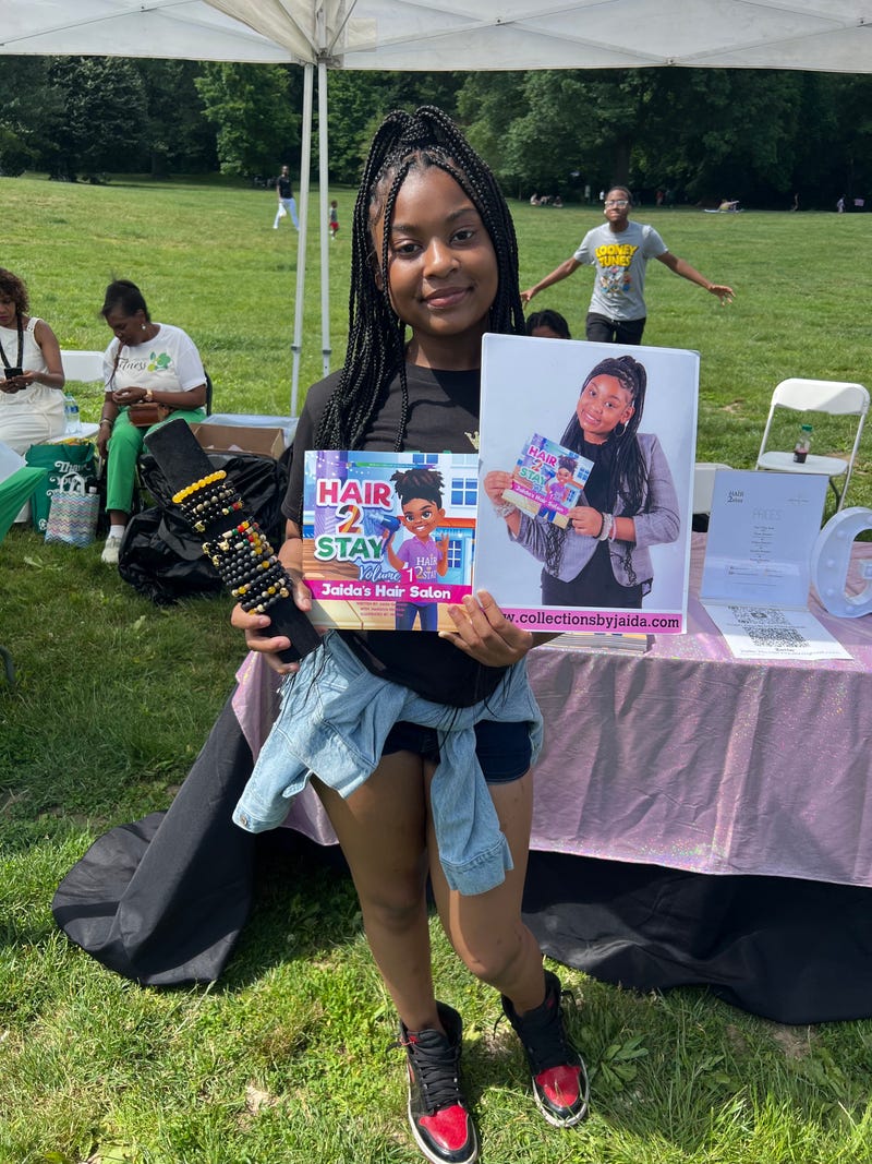 Jaida Germain, the 13-year-old author of "Hair 2 Stay," holds her book and bracelets Sunday