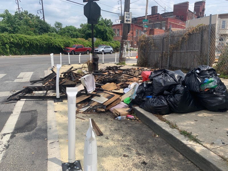 Someone has dumped and set fire to trash behind flexposts on Orianna Street