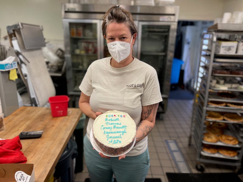 Black Jet Baking Company owner Gillian Lundgren holds a cake with a blunt, NSFW message for the Supreme Court's six conservative justices.