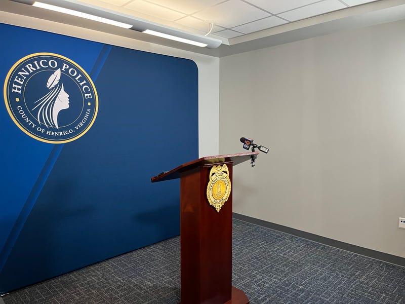 An empty lectern in from of a wall with the "Henrico Police" logo