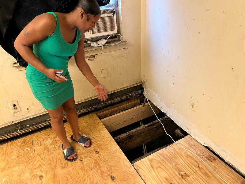 Betzaida Kellum shows the hole in her bedroom floor where mold had been growing.