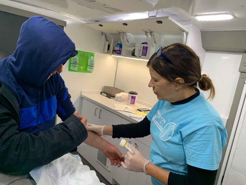 Mary Marquis, a nurse practitioner treating a man inside a van, outfitted by Kensington Hospital, to serve people with wounds from injections of street drugs.
