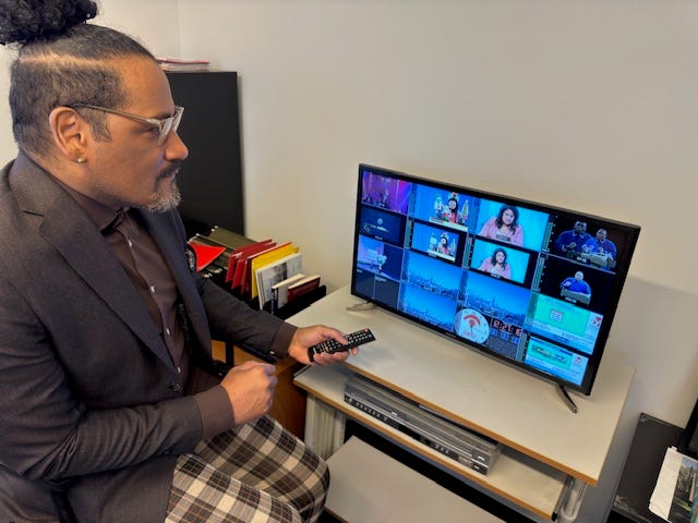 Darrious Hilmon in front of a monitor showing a variety of CAN TV programming