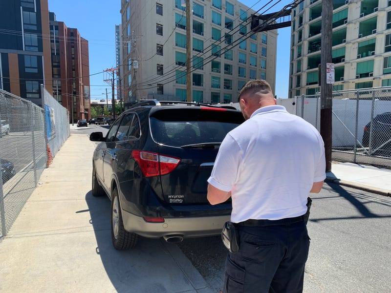 Eric Rossi, parking enforcement supervisor, issues a ticket for a car parked on the sidewalk.