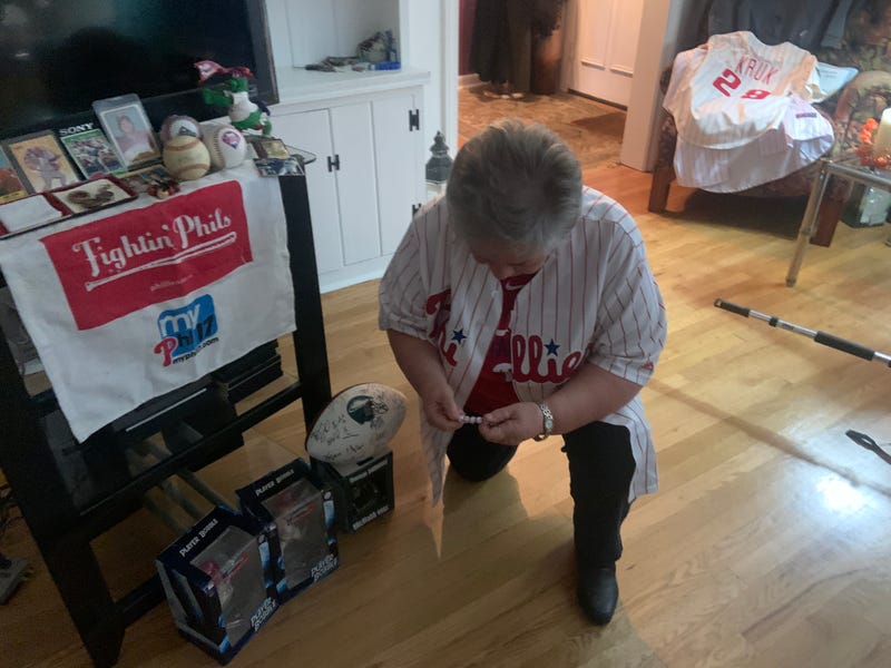 Sr. Linda DeCero kneels in prayer by her "shrine" with many Philadelphia Phillies items alongside her religious relics.