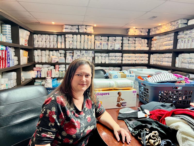 Julie Tracy, Co-Founder of Equipping the Called sits in the basement work and storage area of the charity surrounded by diapers.