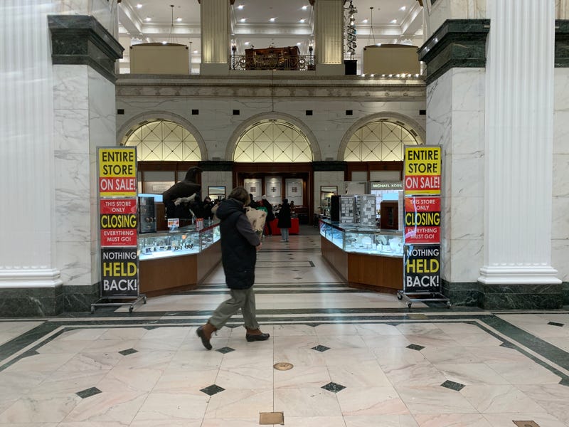 Person walking by Macy's discount signs