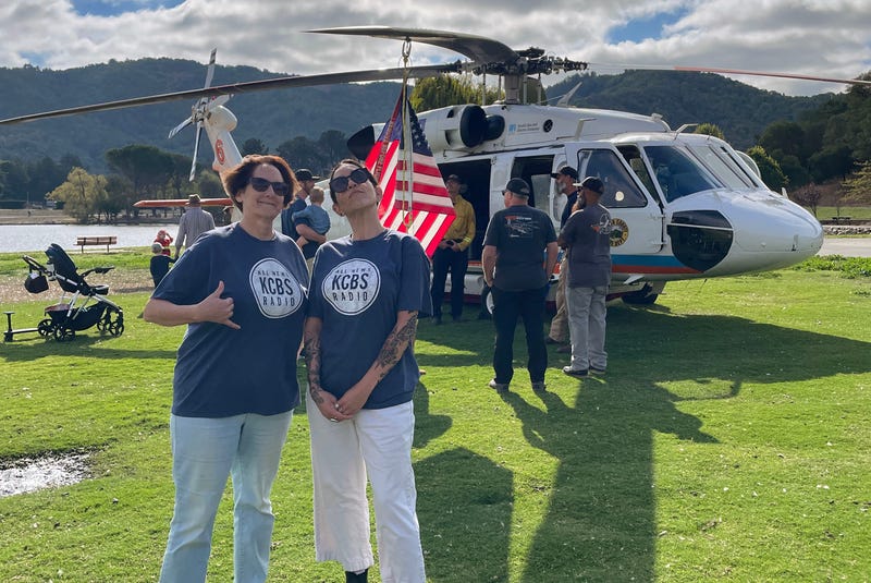 KCBS Radio's Claire Beverly and Danae Labrana stand in front of a Marin County fire helicopter at Ember Stomp 2025.