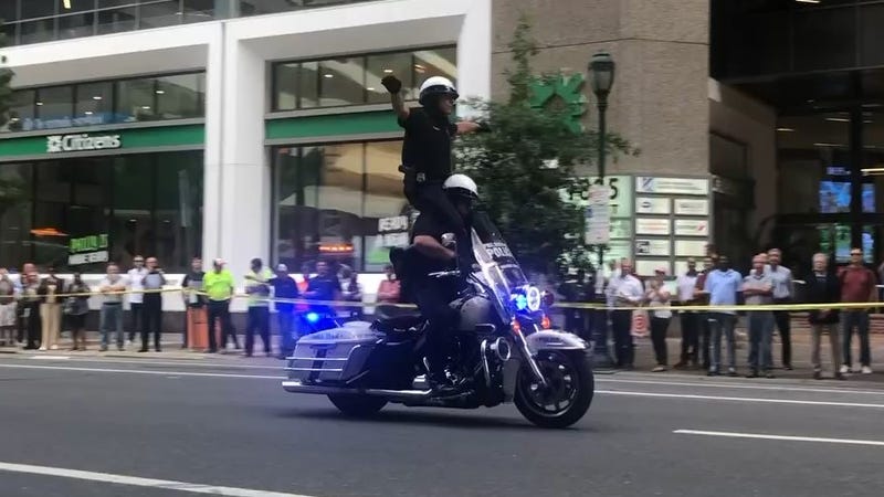Two Philadelphia Police officers doing a motorcycle trick on Market Street to promote the Hero Thrill Show on Saturday at the Wells Fargo Center.