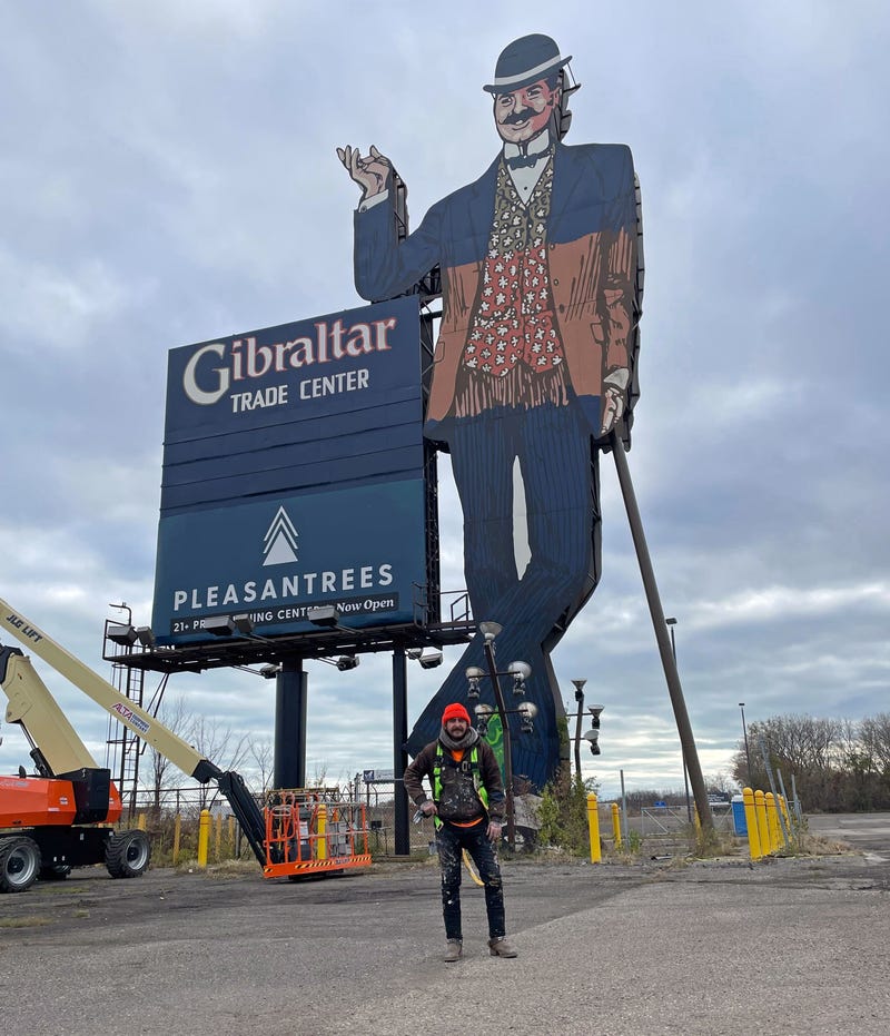 Painter Zak Warmann stands in front of the Gibraltar Trade Center sign in Mount Clemens, Mich., which he is retouching for Pleasantrees