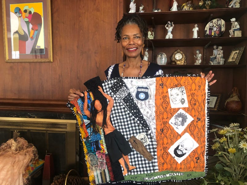 Gloria Davis, one of the contributing artists, holds one of her quilts, which is in the exhibit.