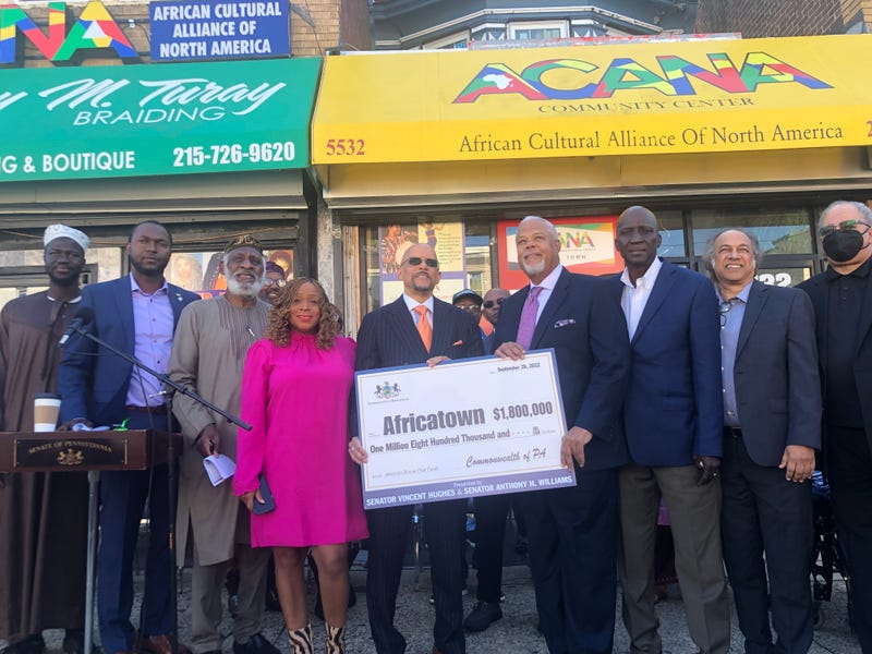 Pennsylvania state senators Vincent Hughes and Anthony Hardy Williams, center, hold a check for $1.8 million to contribute to the development of a commuity called Africatown in Southwest Philadelphia.