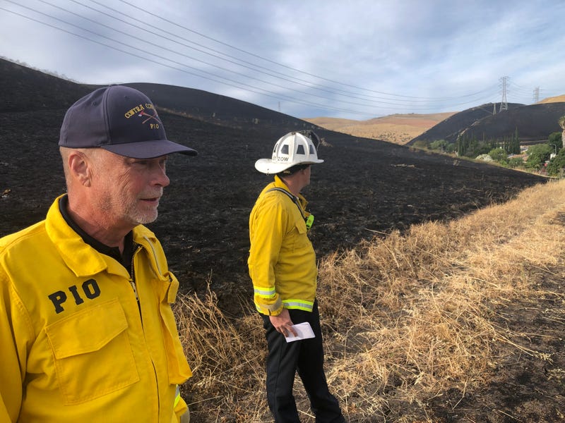 Contra Costa County Fire officials survey the blackened hillsides of the neighborhood.