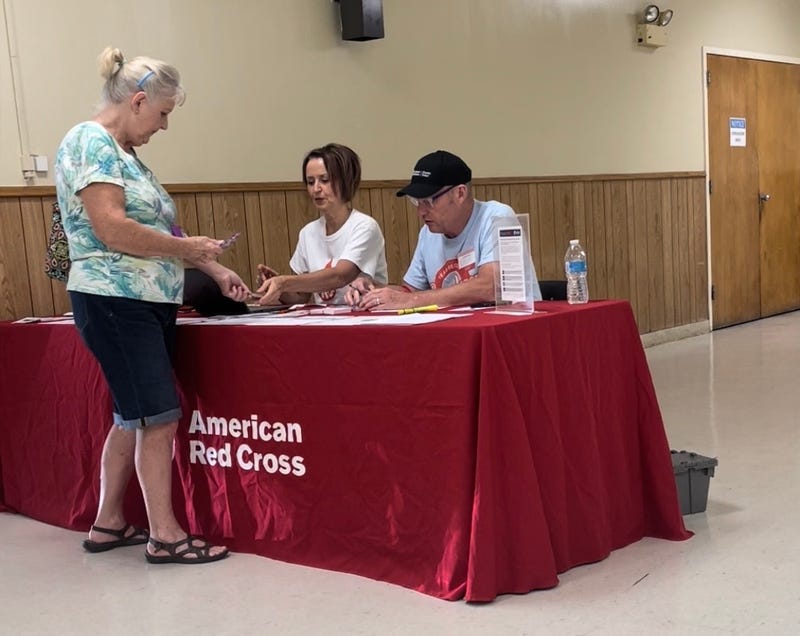 Two red cross volunteers check in a person about to donate blood
