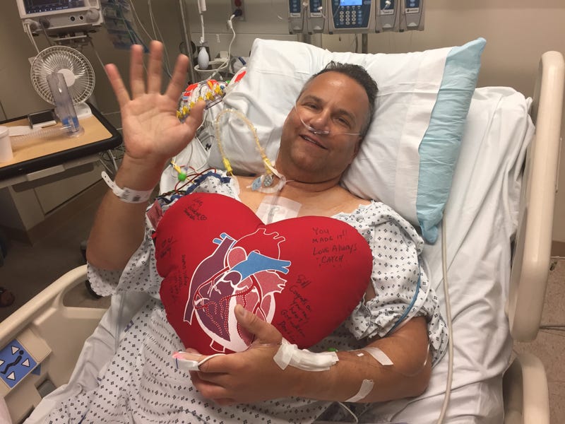 Bill Soloway laying in a hospital bed with a signed heart pillow.