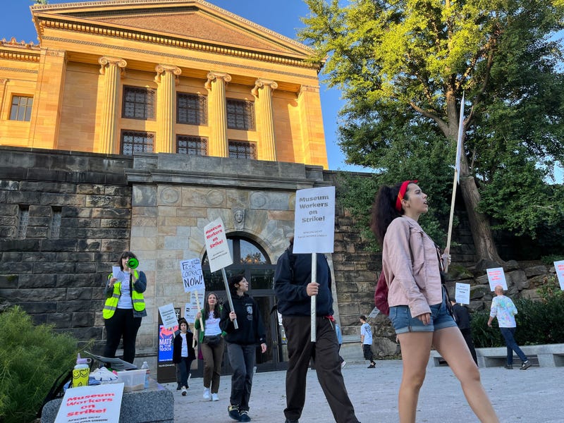 Philadelphia Museum of Art employees hold picket signs in front of a museum entrance.