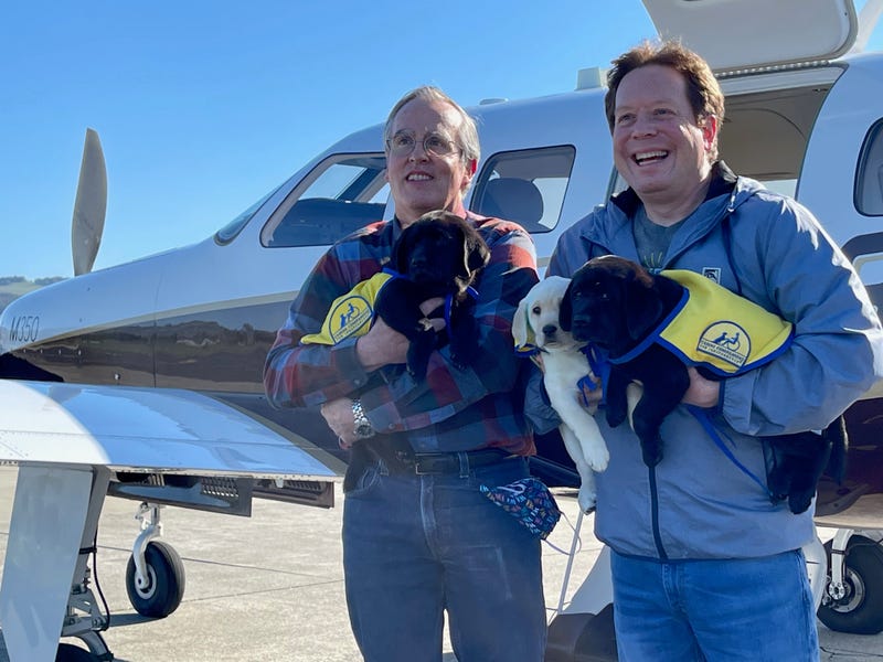 Pilot David Tuckerman and his husband, Kenny, with some of the eight-week-old puppies taking flight on Friday morning.