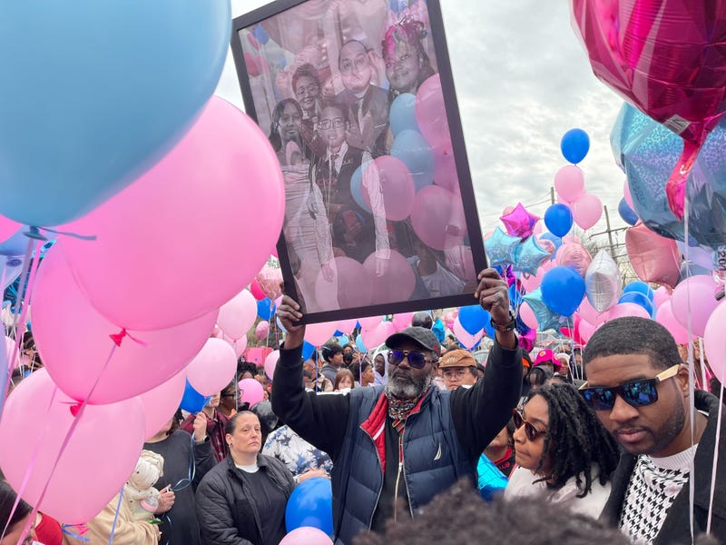 A community member holds aloft a portrait of the Le family at a memorial balloon release in Yeadon on Saturday.
