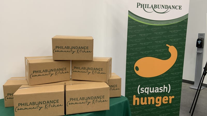 Philabundance Community Kitchen boxes next to a "(squash) hunger" banner
