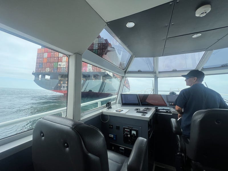captain in boat with container ship outside the window