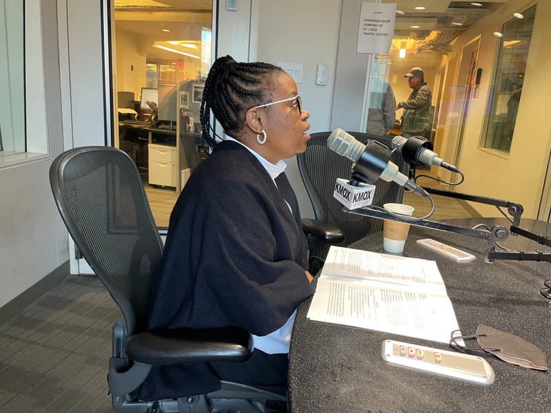 dr. mati hlatshwayo davis speaks at a mic in the kmox studio. she's a black woman with braids in a ponytail wearing glasses and a black sweater.