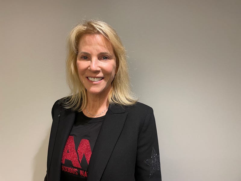 laura morton headshot. she's a white woman with shoulder-length blond hair, an anxious nation tshirt and a black blazer