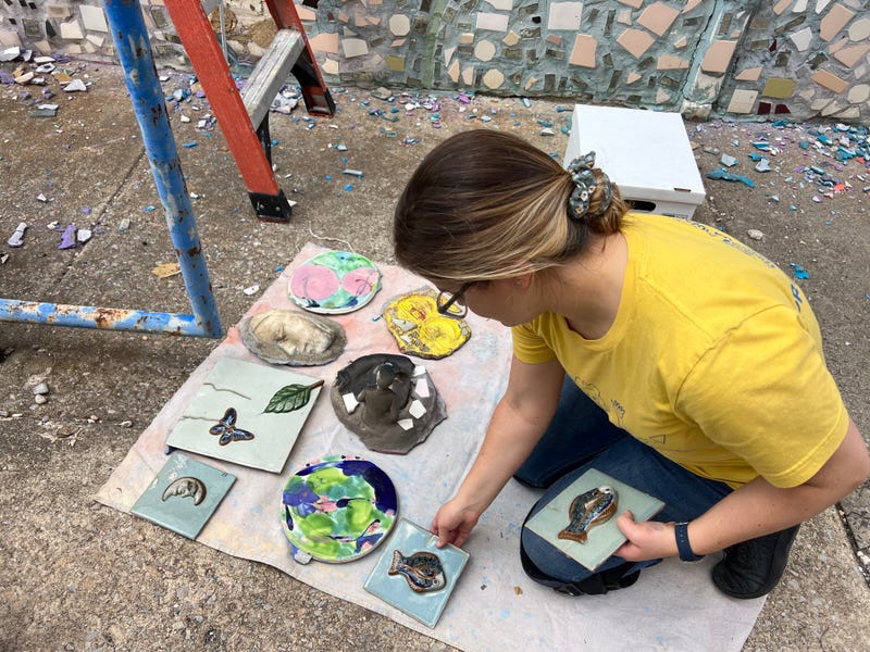 A woman works to take down mosaic tiles from the Painted Bride Art Center's walls.