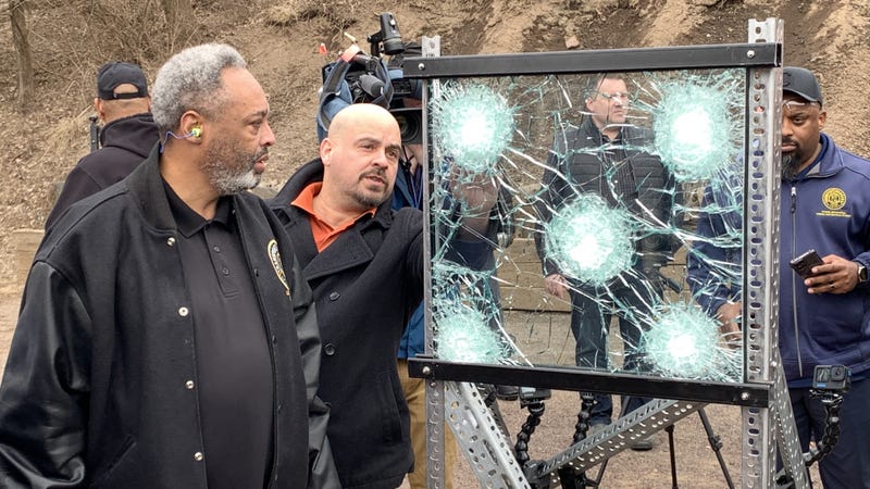 SWAT team members, SEPTA and union officials look at the results of a bulletproof glass test.