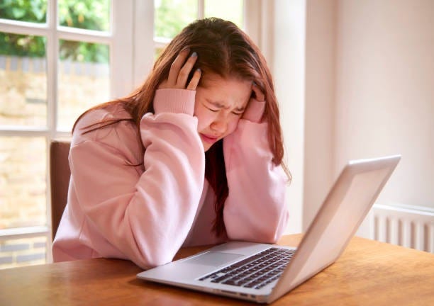 teenage girl crying using laptop