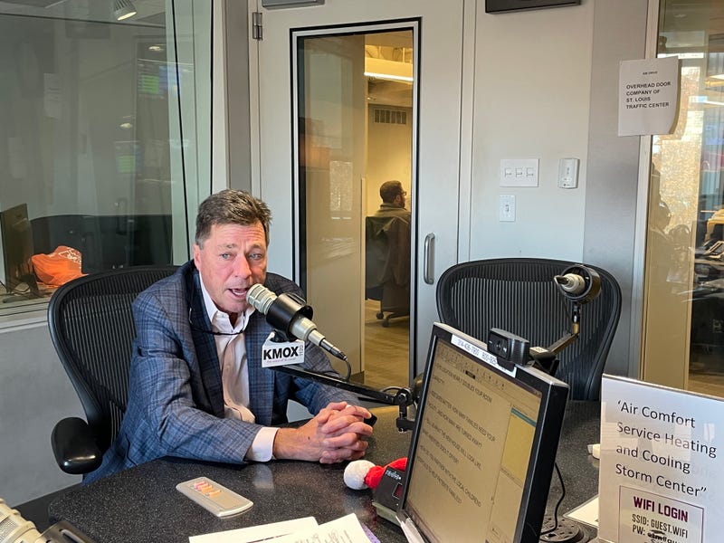 dan harbaugh. white man with brown hair and blue suit speaking into KMOX microphone.