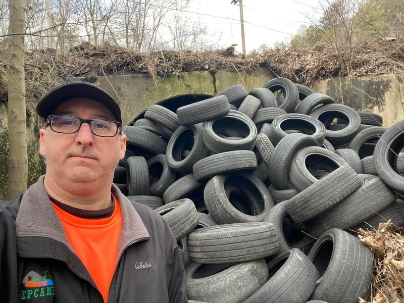 Earth Conservancy Executive Director Bobby Hughes in front of illegal tire dump in the Nanticoke Creek watershed near Earth Conservancy entrance. 