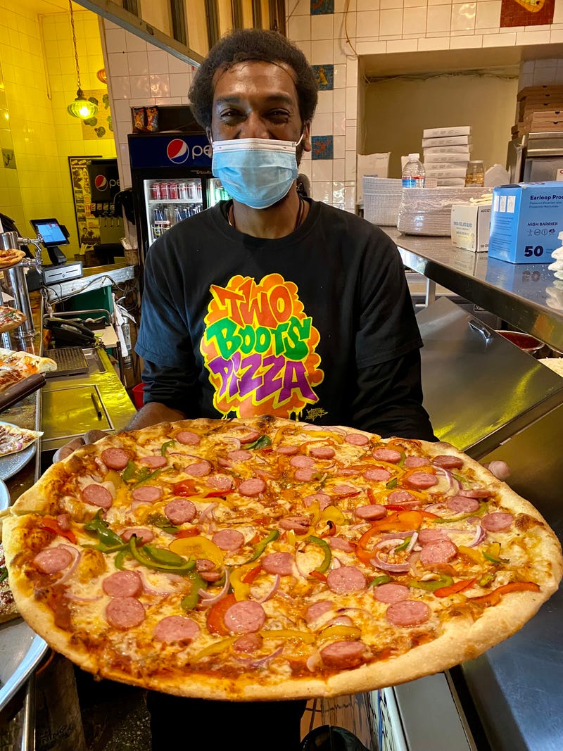 Two Boots employee Michael Perry shows off a fresh-out-of-the-oven "Mr. Ze" pizza at the chain's East Village location. 