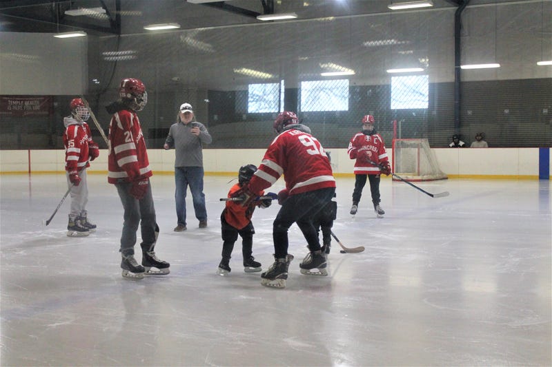 Volunteers from the Penncrest High School hockey team helping a visually impaired player, Benjamin, skate.