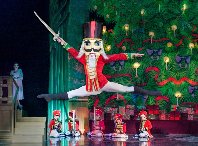 The Nutcracker Prince in a grand jete in front of a Christmas tree and toy soldiers