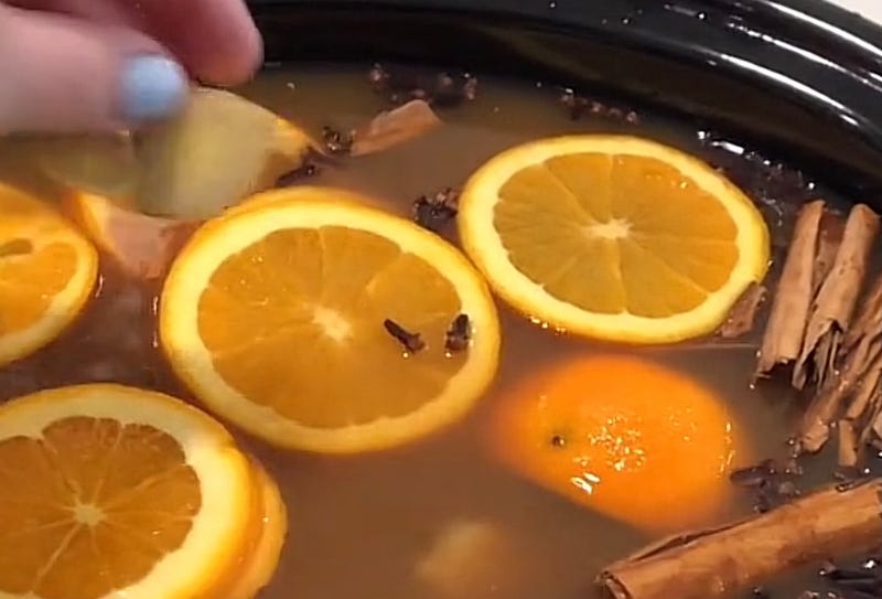 Mulled cider with orange slices, cinnamon, and cloves in a slow cooker