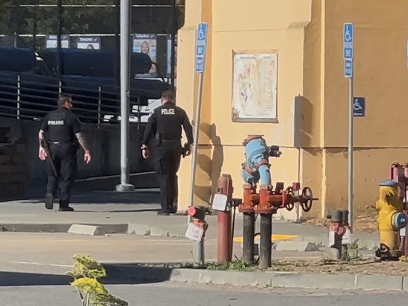 Police officers on a sidewalk walking around the building of Tamalpais High School
