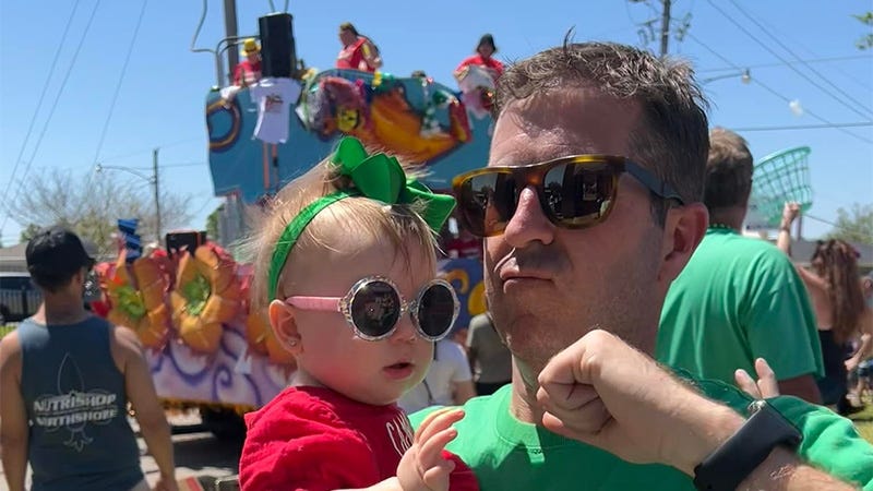 man and baby dance with parade float in background