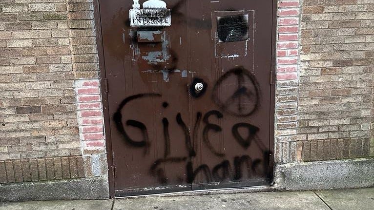 The front door of a mosque, with "Give peace a chance" spray-painted across it.