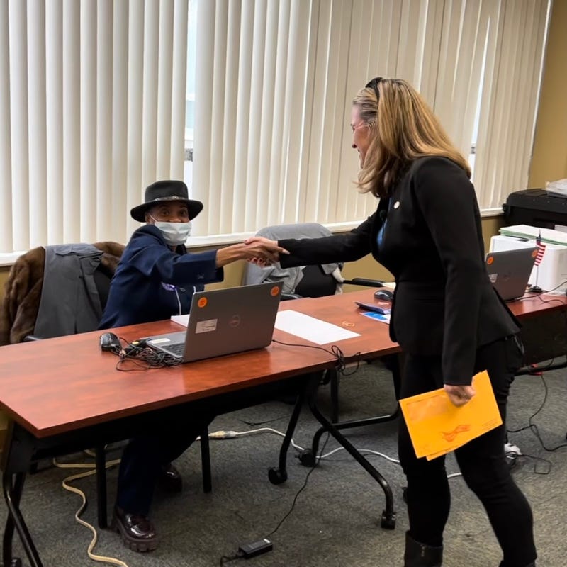 An election worker at Detroit's Northwest Activities Center early voting site greets Secretary Benson as she prepares to cast her ballot.