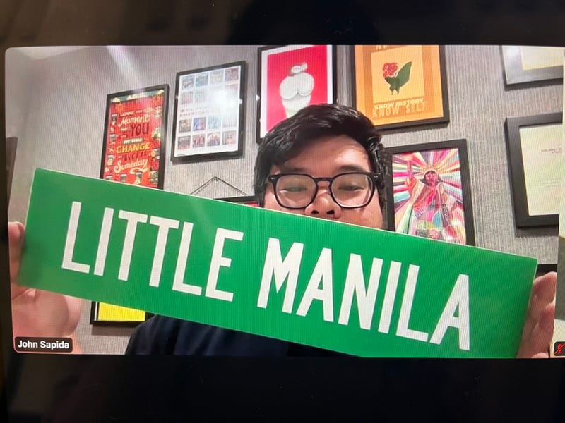 John Sapida holds up a "Little Manila" street sign