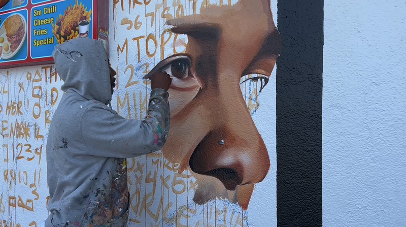 man painting mural on side of building
