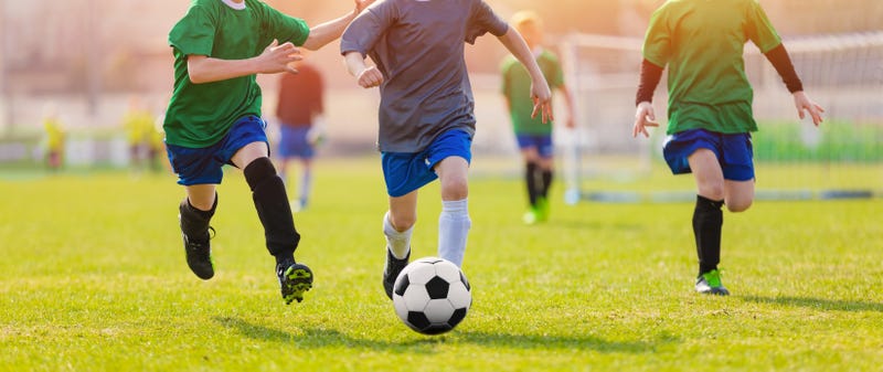 Young Soccer Players Running After the Ball. Soccer Stadium in the Background