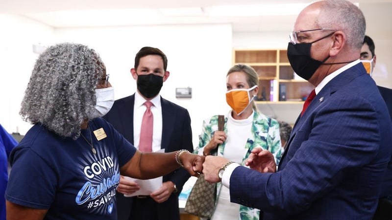 Nurse Carla Brown (L) fist bumps Louisiana Gov. John Bel Edwards at an event where the governor honored her for her vaccine work on August 17, 2021 in Baton Rouge, Louisiana.