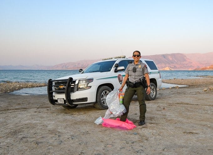 A Lake Mead ranger poses with prohibited pool toys with the lake in the background